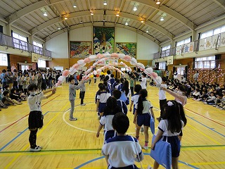 花のアーチを通る1年生の画像